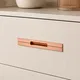 HA 00205 N Ottr Concealed Handle Rose Gold Dual Tone Finish 24in â close-up of rose gold handle on cream drawer