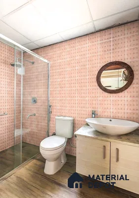 Modern bathroom with peach patterned wall tiles, wood-look floor tiles, and marble countertop vanity