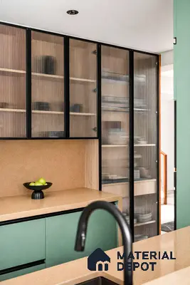 Modern kitchen with sage green laminate cabinets, beige quartz countertop, and fluted glass pantry shutters