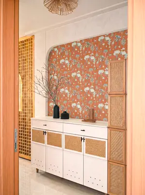 Scandinavian foyer with terracotta floral wallpaper, white cabinet, and cane panel accents