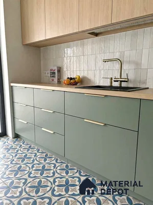 Scandinavian kitchen with sage green laminate cabinets, light wood laminate, and blue patterned floor tiles