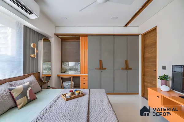 Modern bedroom with grey and orange dual tone wardrobe, fluted panel, and wooden accents of 3 BHK apartment in Mahaveer Rich Jalahalli Bengaluru