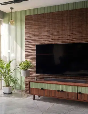 Mid-century modern TV unit with sage green fluted laminate, walnut wood laminate, and marble look floor tile in 3 BHK apartment Vaishnavi Rathnam Jalahalli Bengaluru
