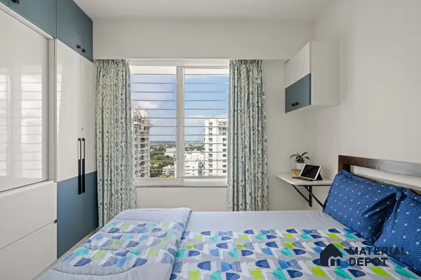 Modern bedroom with blue and white laminate wardrobe and floral curtains of 2 BHK in Purva Palm Beach Hennur Bengaluru | Material Depot