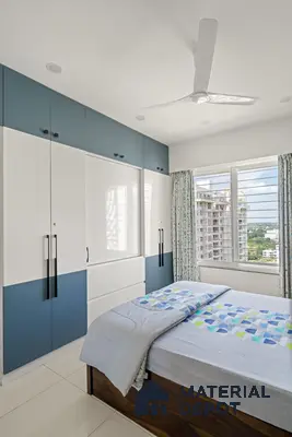 Modern bedroom with dual tone blue and white laminate wardrobe and wooden bed frame of 2 BHK in Purva Palm Beach Hennur Bengaluru | Material Depot
