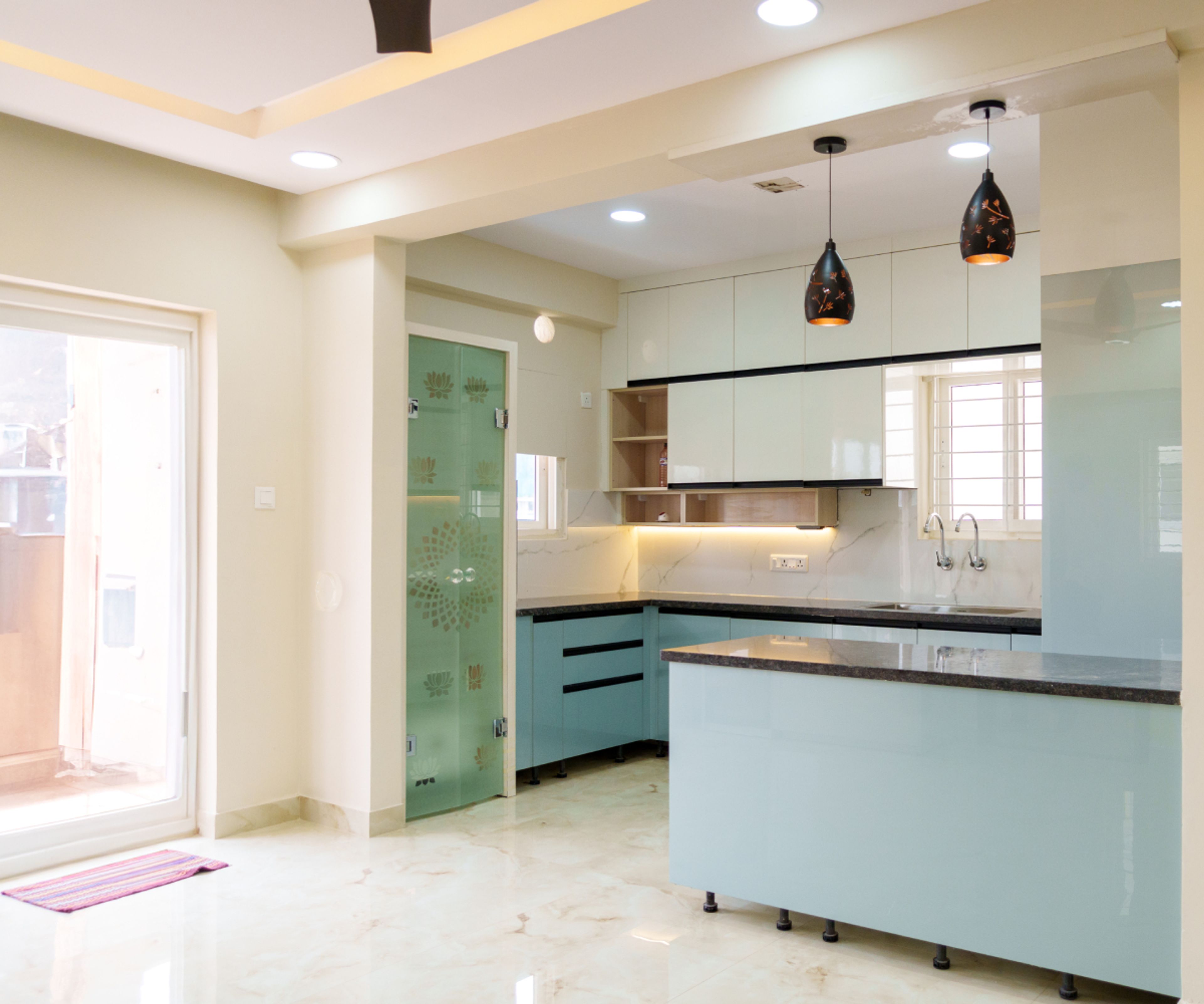 Modern dual tone kitchen with pastel blue and frosty white laminate, black granite countertop, and marble look floor tile in Bengaluru | Material Depot