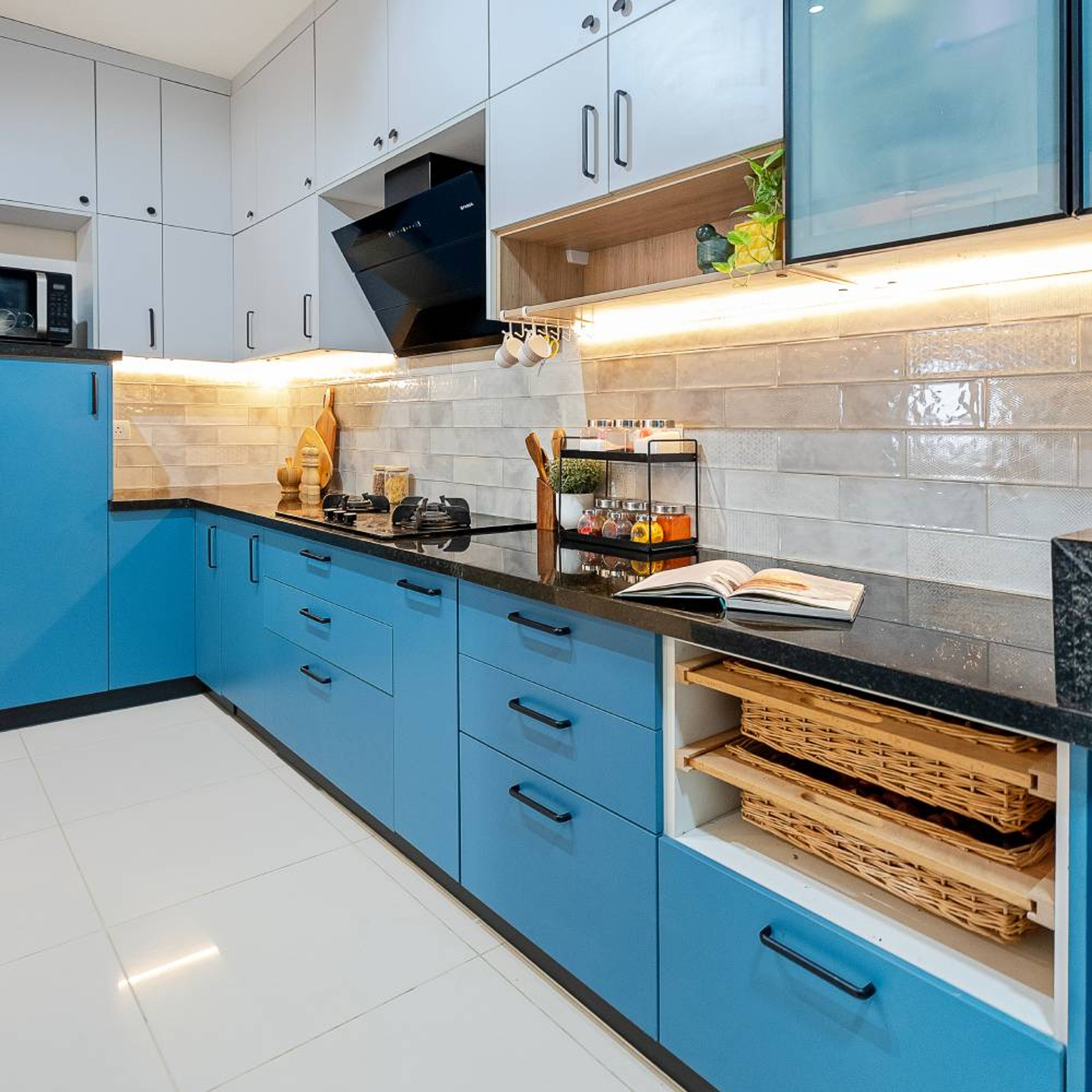 Modern dual tone kitchen with sky blue and frosty white laminate, black granite countertop, and beige subway backsplash tiles in Bengaluru | Material Depot