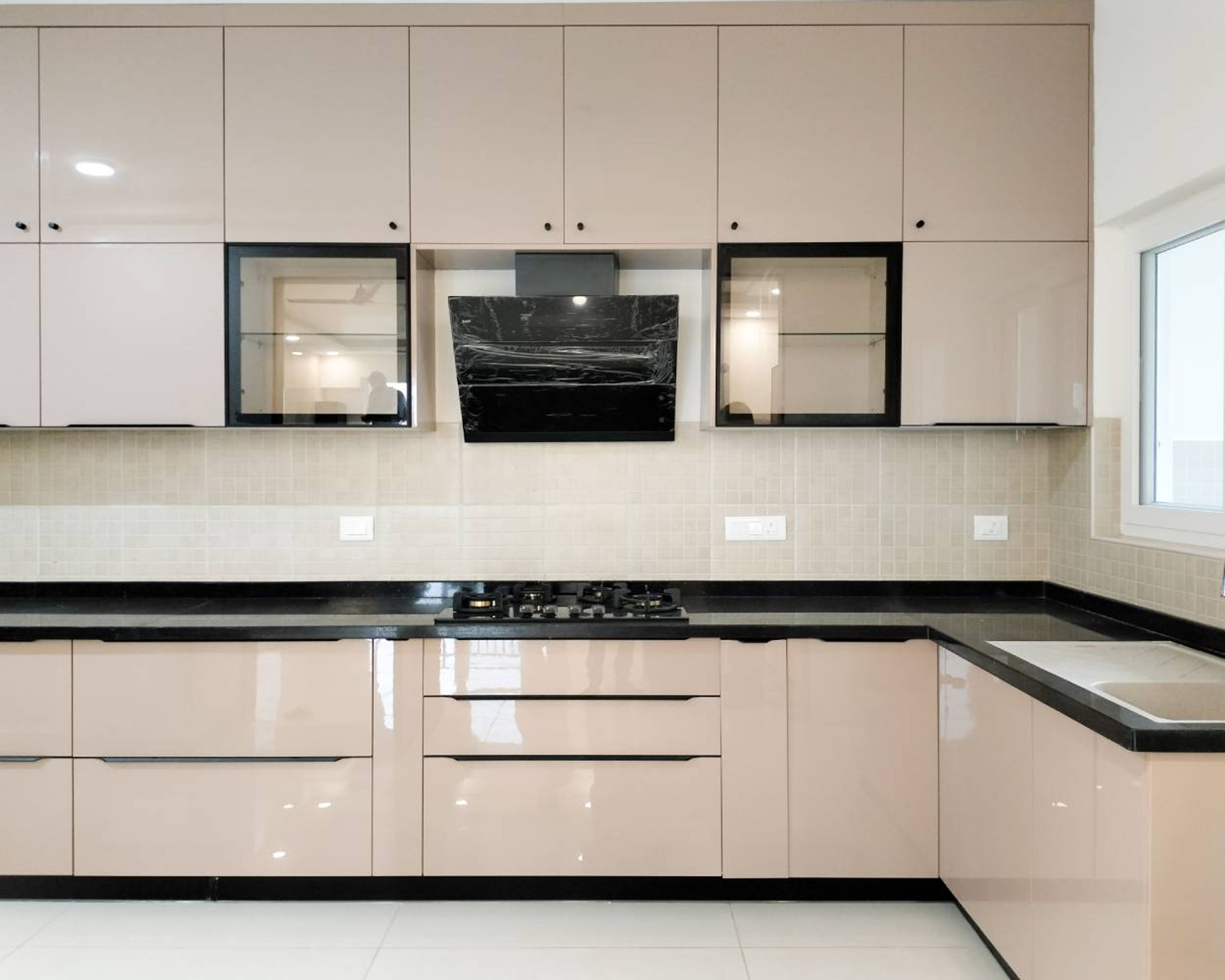 Modern kitchen with beige high gloss laminate cabinets, black granite countertop, and beige mosaic backsplash tiles in Bengaluru | Material Depot