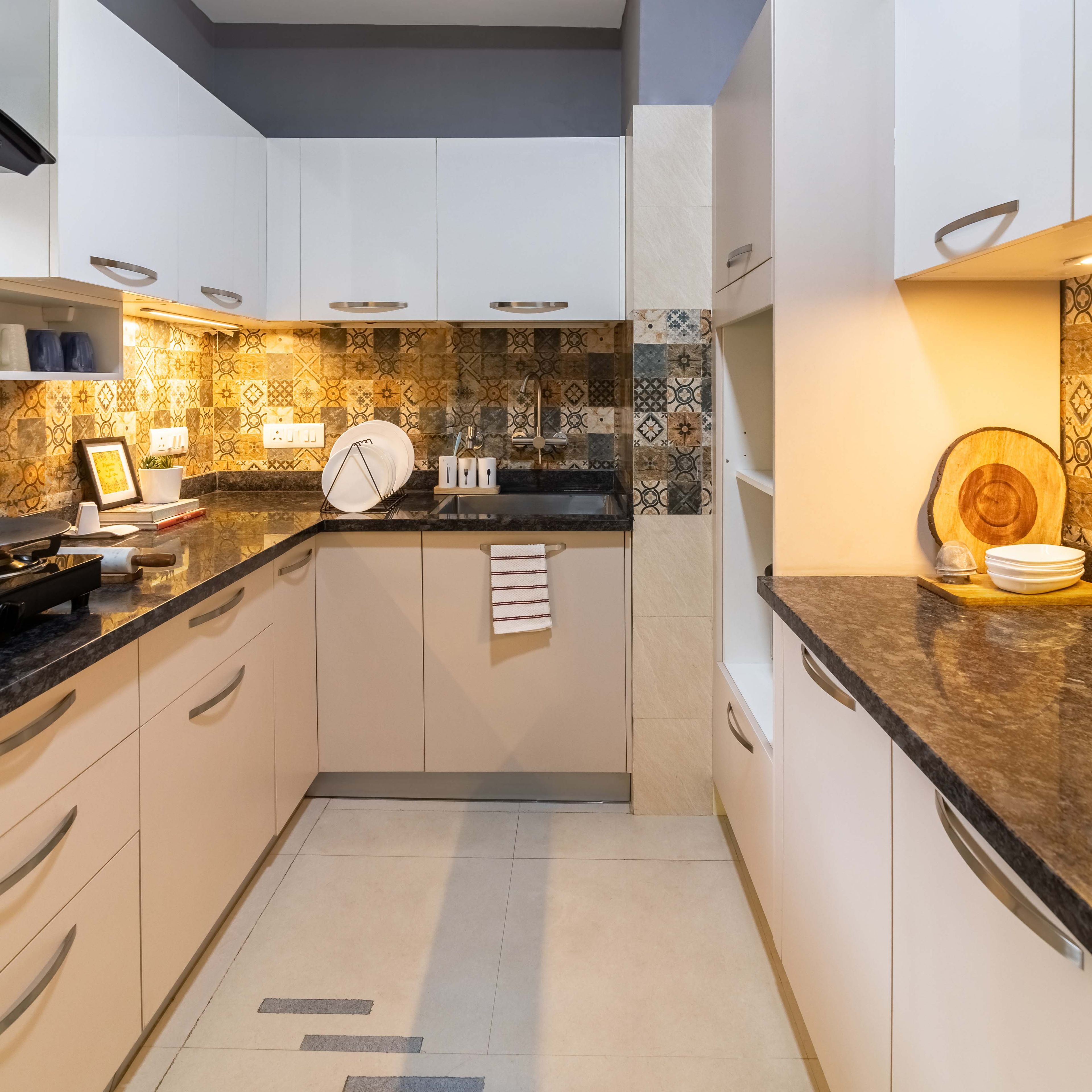 Modern kitchen with beige laminate cabinets, patterned moroccan backsplash tiles, and black granite countertop in Bengaluru | Material Depot