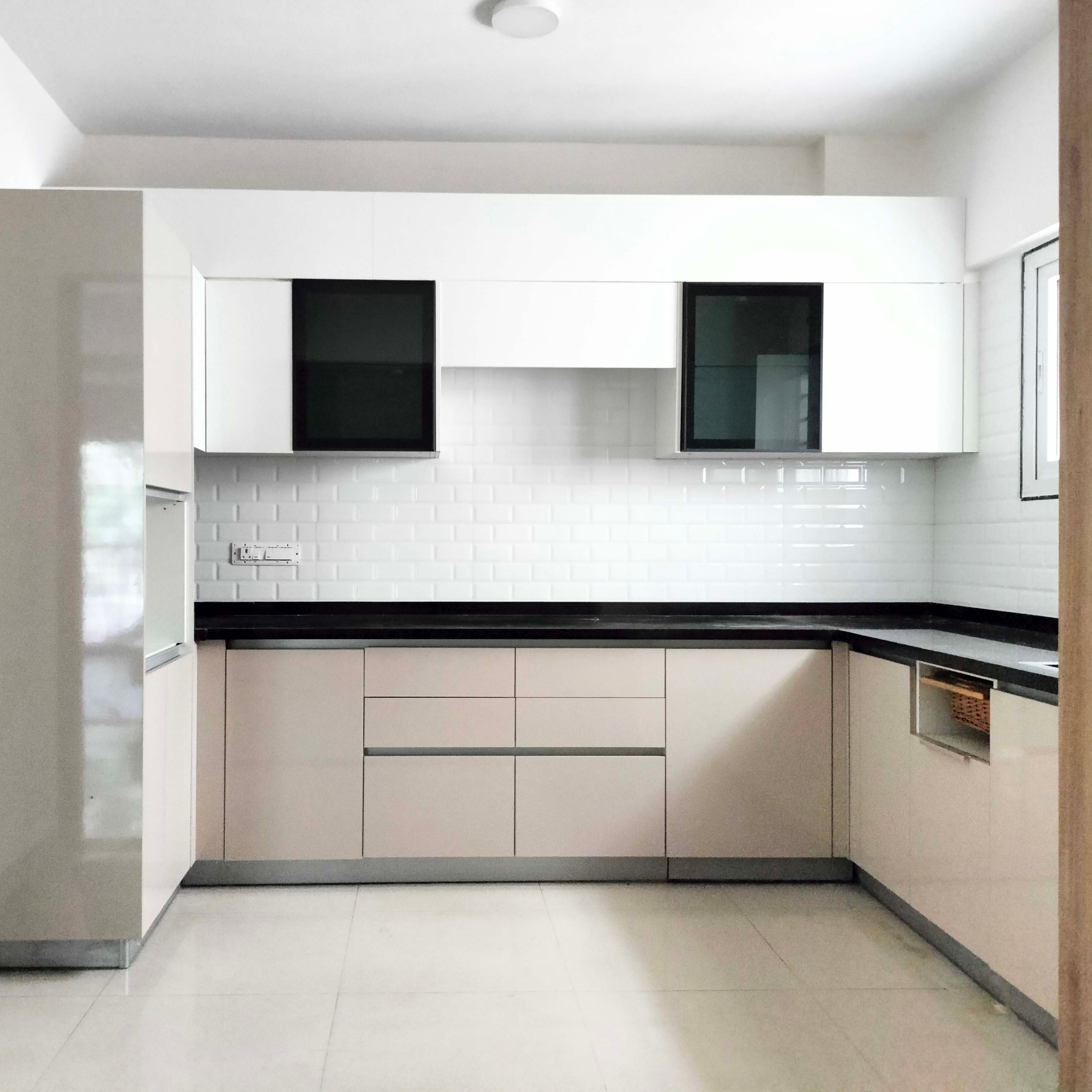Modern kitchen with glossy beige laminate cabinets, black countertop, and white subway tile backsplash in Bengaluru | Material Depot