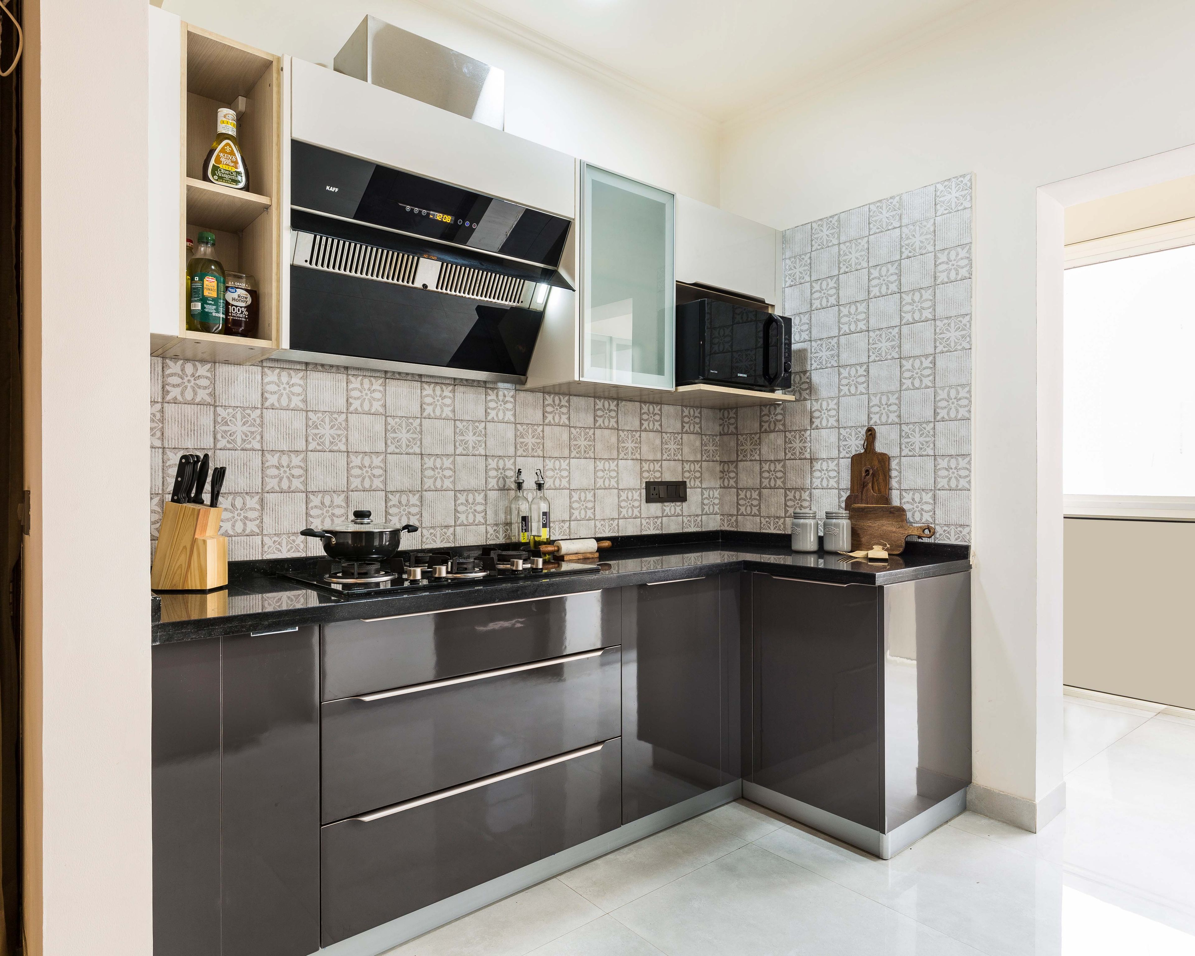 Modern kitchen with grey high gloss laminate, black granite countertop, and patterned grey backsplash tiles in Bengaluru | Material Depot