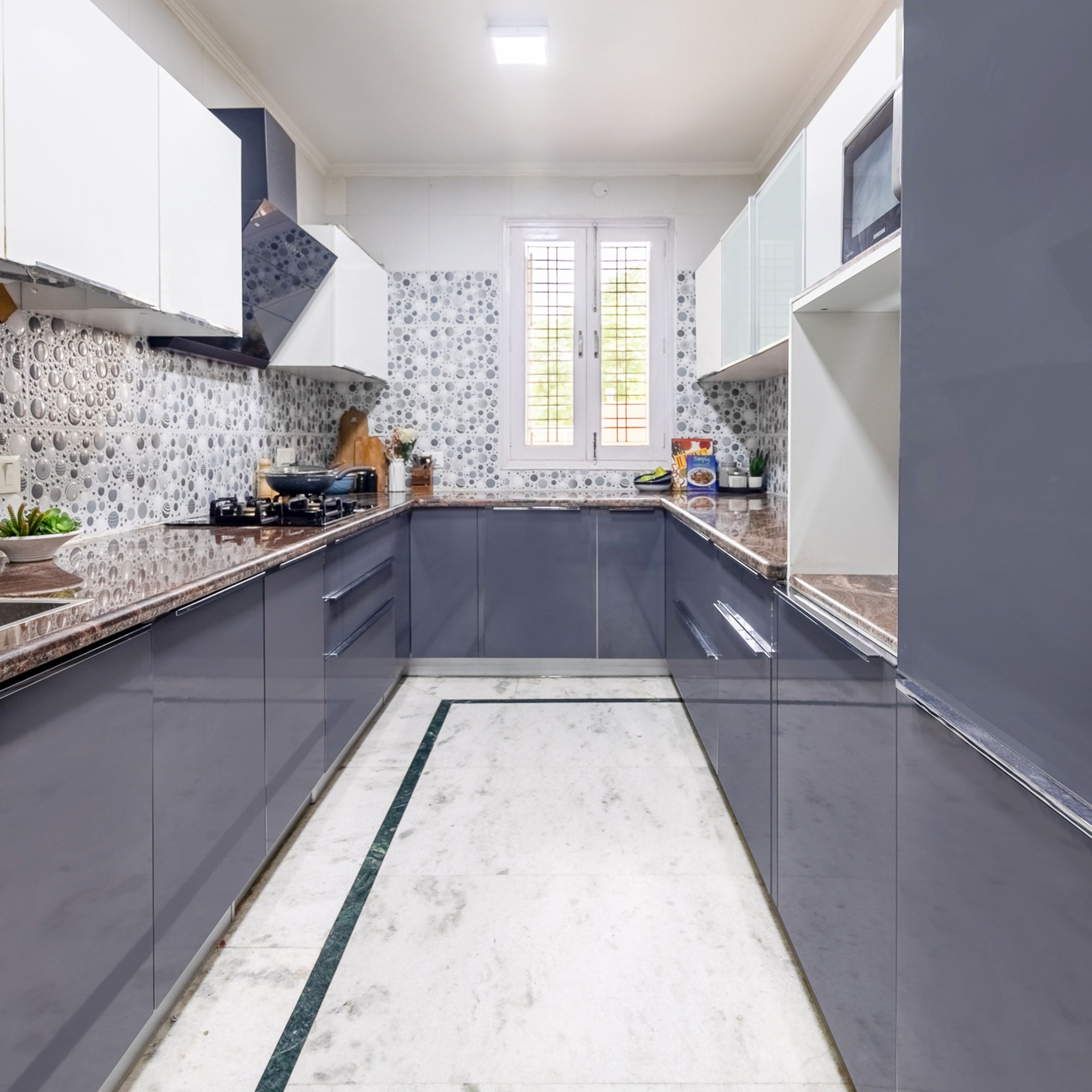Modern kitchen with grey high gloss laminate, patterned backsplash tile, and marble floor in Bengaluru | Material Depot
