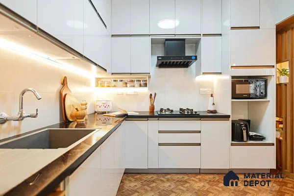 Modern kitchen with high gloss white laminate cabinets, black granite countertop, and wood-look floor tiles in Bengaluru | Material Depot