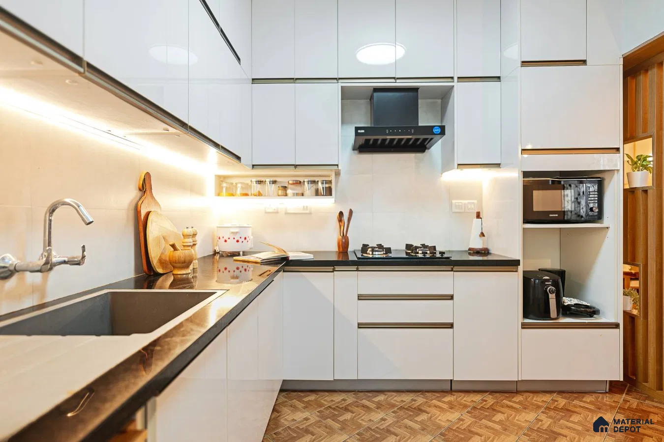 Modern kitchen with high gloss white laminate cabinets, black granite countertop, and wood-look floor tiles in Bengaluru | Material Depot