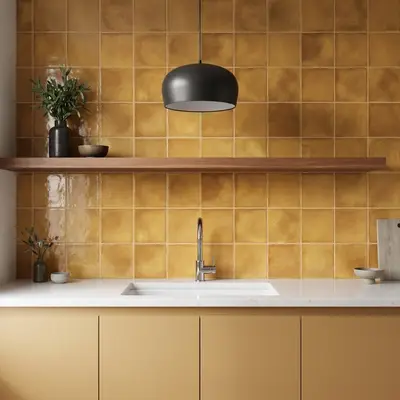 Modern kitchen with mustard yellow square wall tiles and matte beige laminate cabinets