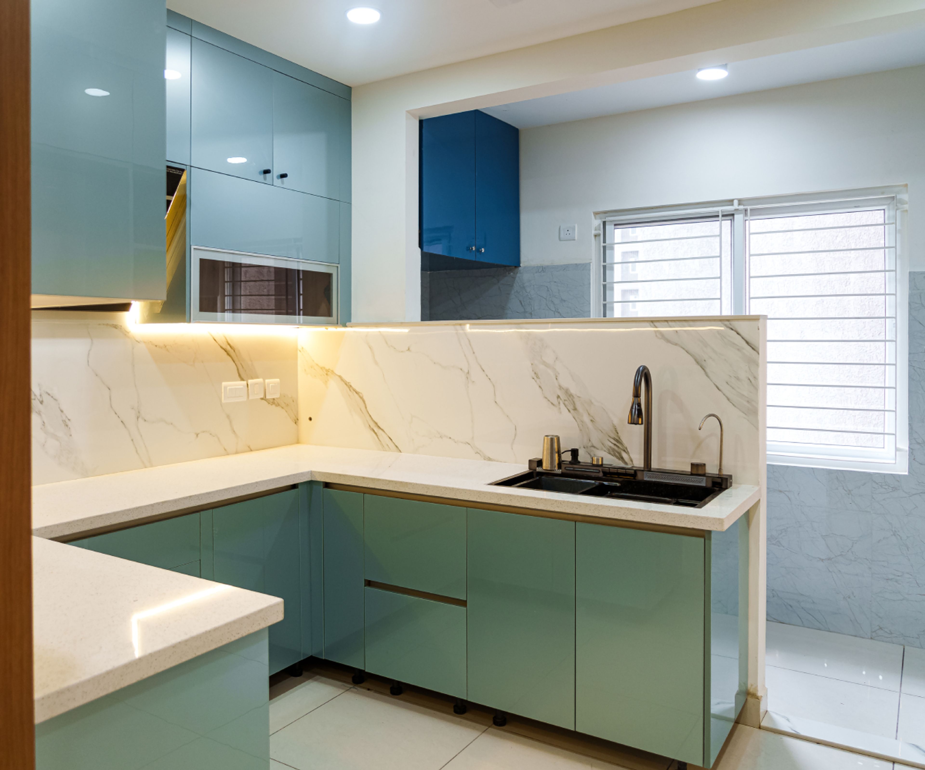 Modern kitchen with pastel blue glossy laminate, white marble-look backsplash tile, and white quartz countertop in Bengaluru | Material Depot