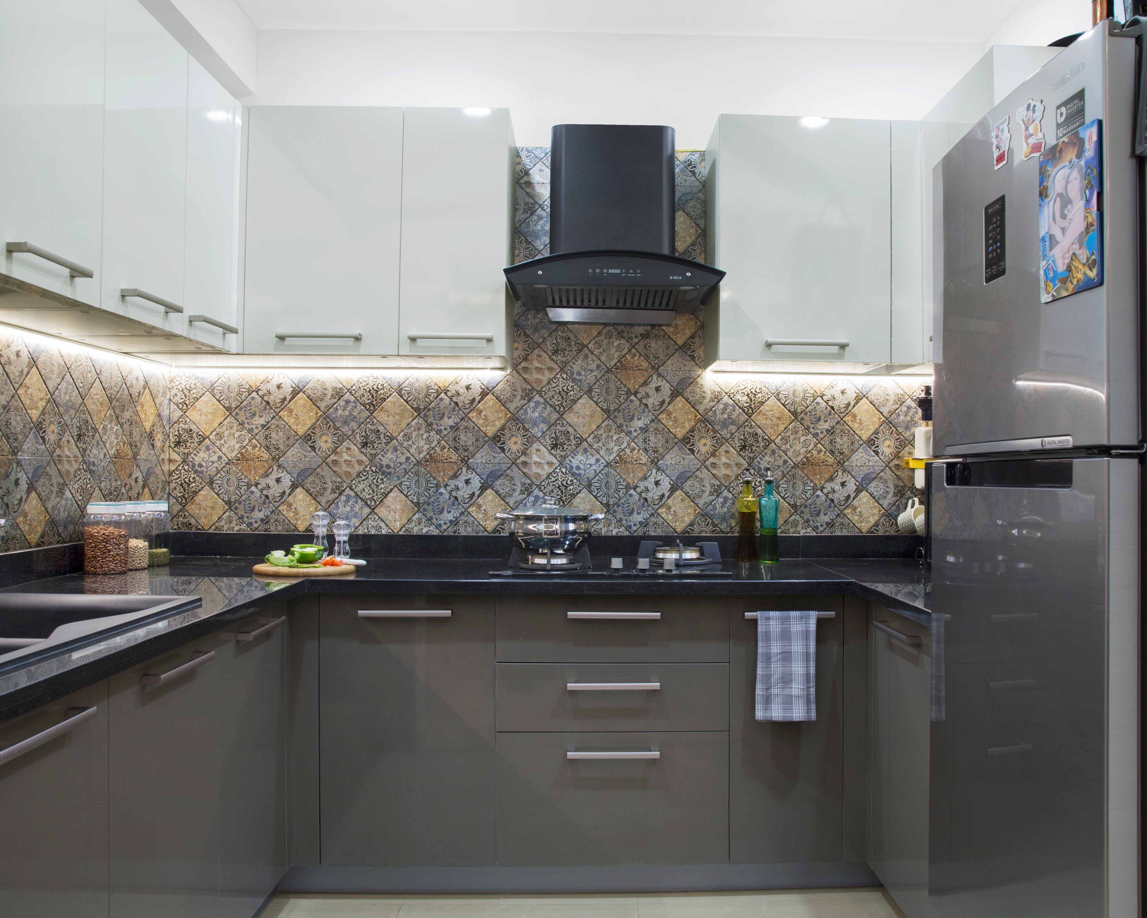 Modern kitchen with patterned moroccan backsplash tiles, glossy white and grey laminate cabinets, and black granite countertop in Bengaluru | Material Depot