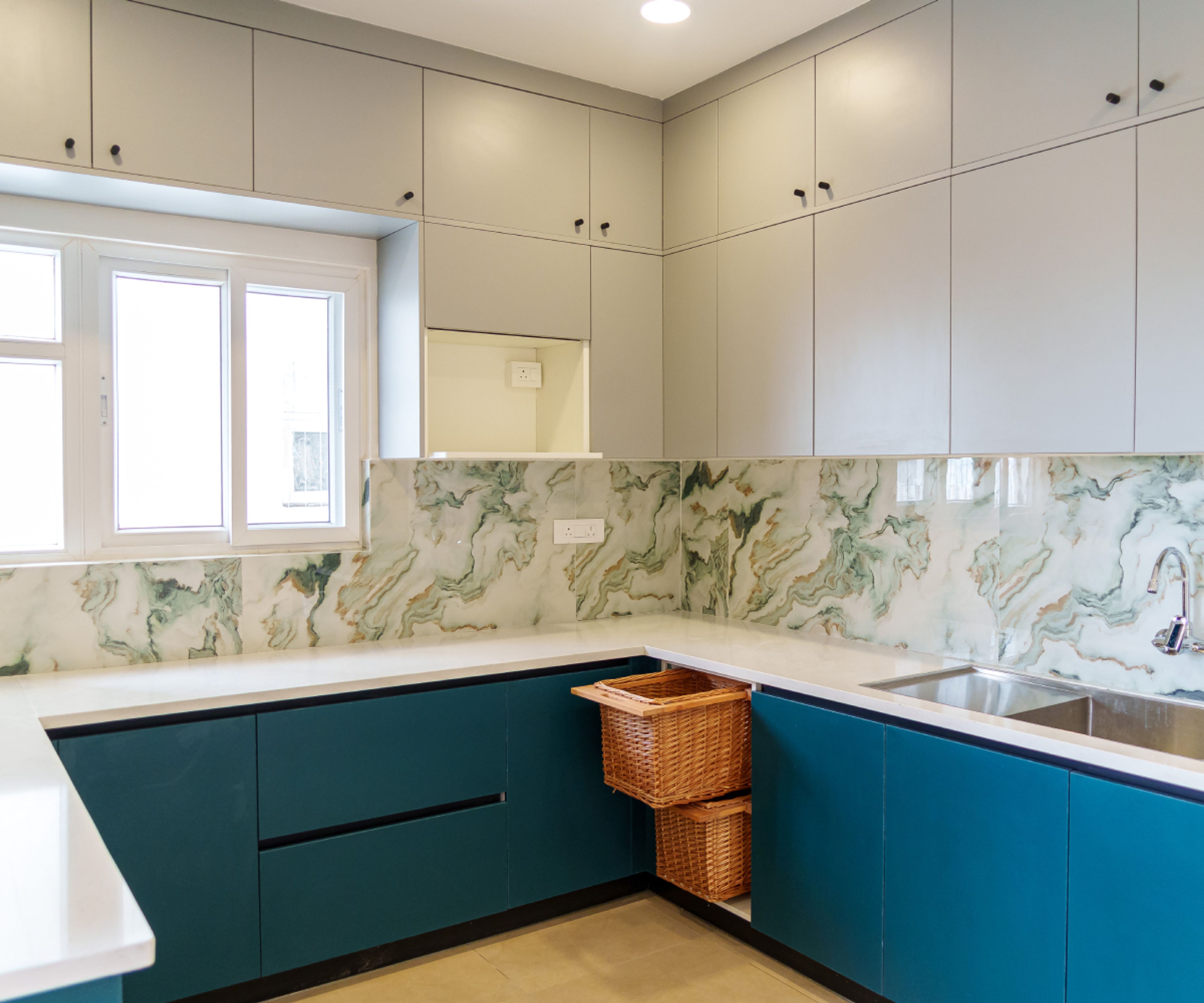 Modern kitchen with teal blue and light grey laminate, marble-look backsplash tile, and white quartz countertop in Bengaluru | Material Depot