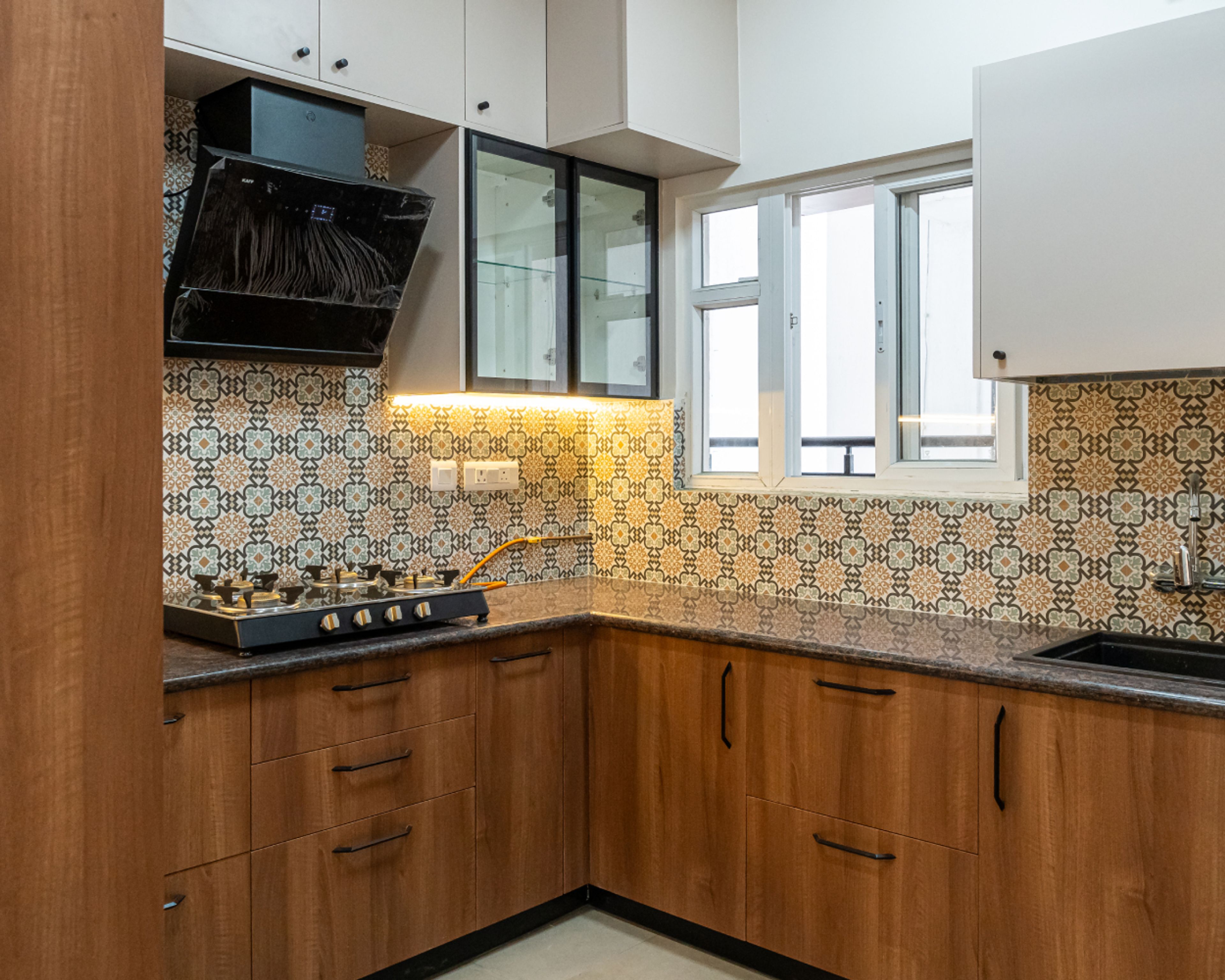 Modern kitchen with walnut brown wood laminate, patterned moroccan backsplash tiles, and dark granite countertop in Bengaluru | Material Depot