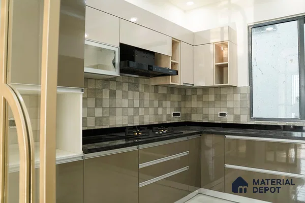 Modern L-shaped kitchen with glossy beige and taupe laminate, black granite countertop, and grey checkered backsplash tiles in Bengaluru | Material Depot