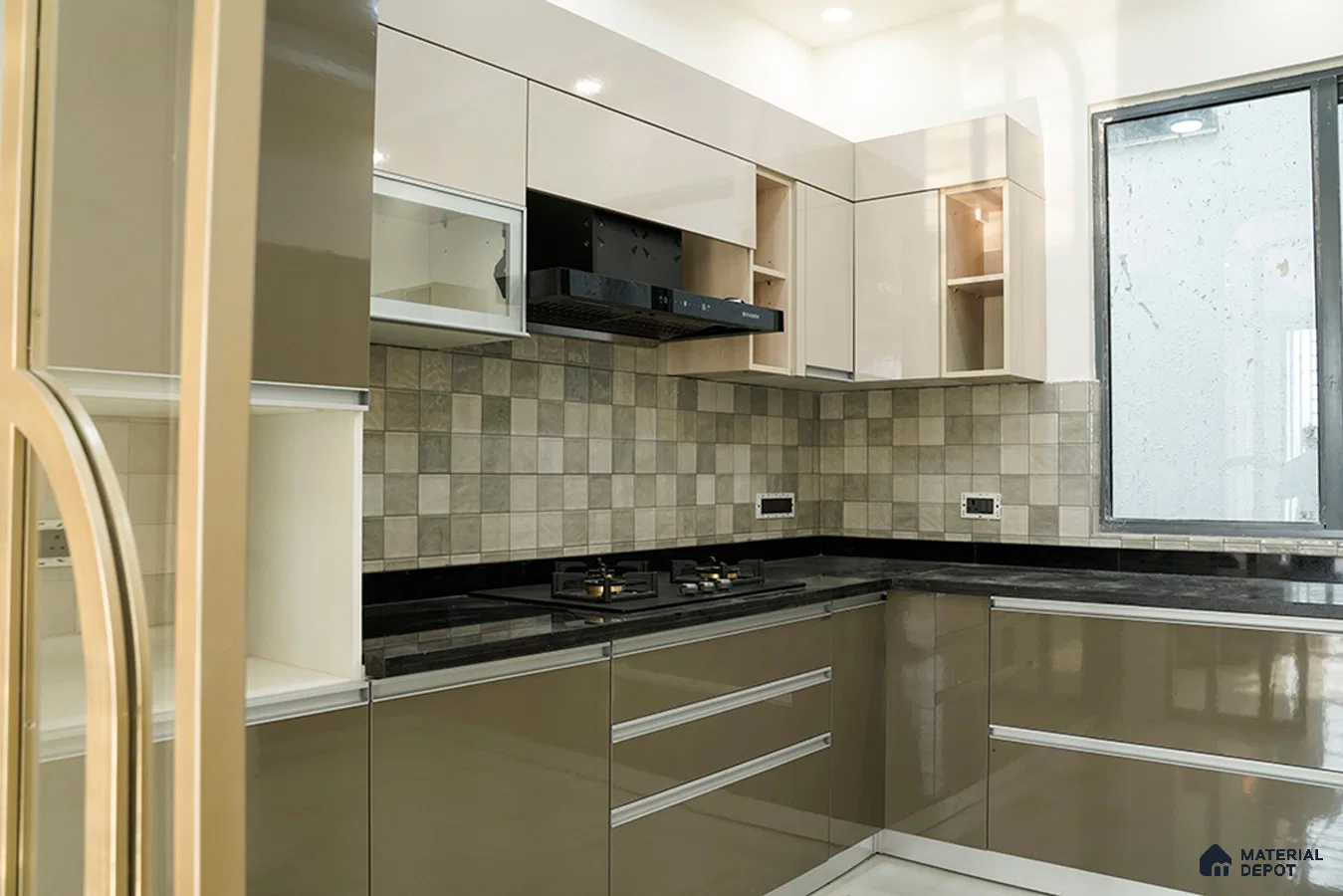 Modern L-shaped kitchen with glossy beige and taupe laminate, black granite countertop, and grey checkered backsplash tiles in Bengaluru | Material Depot