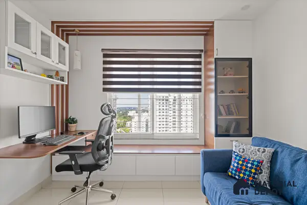 Modern study room with walnut wood laminate desk, white laminate cabinetry, and blue fabric sofa of 2 BHK in Purva Palm Beach Hennur Bengaluru | Material Depot