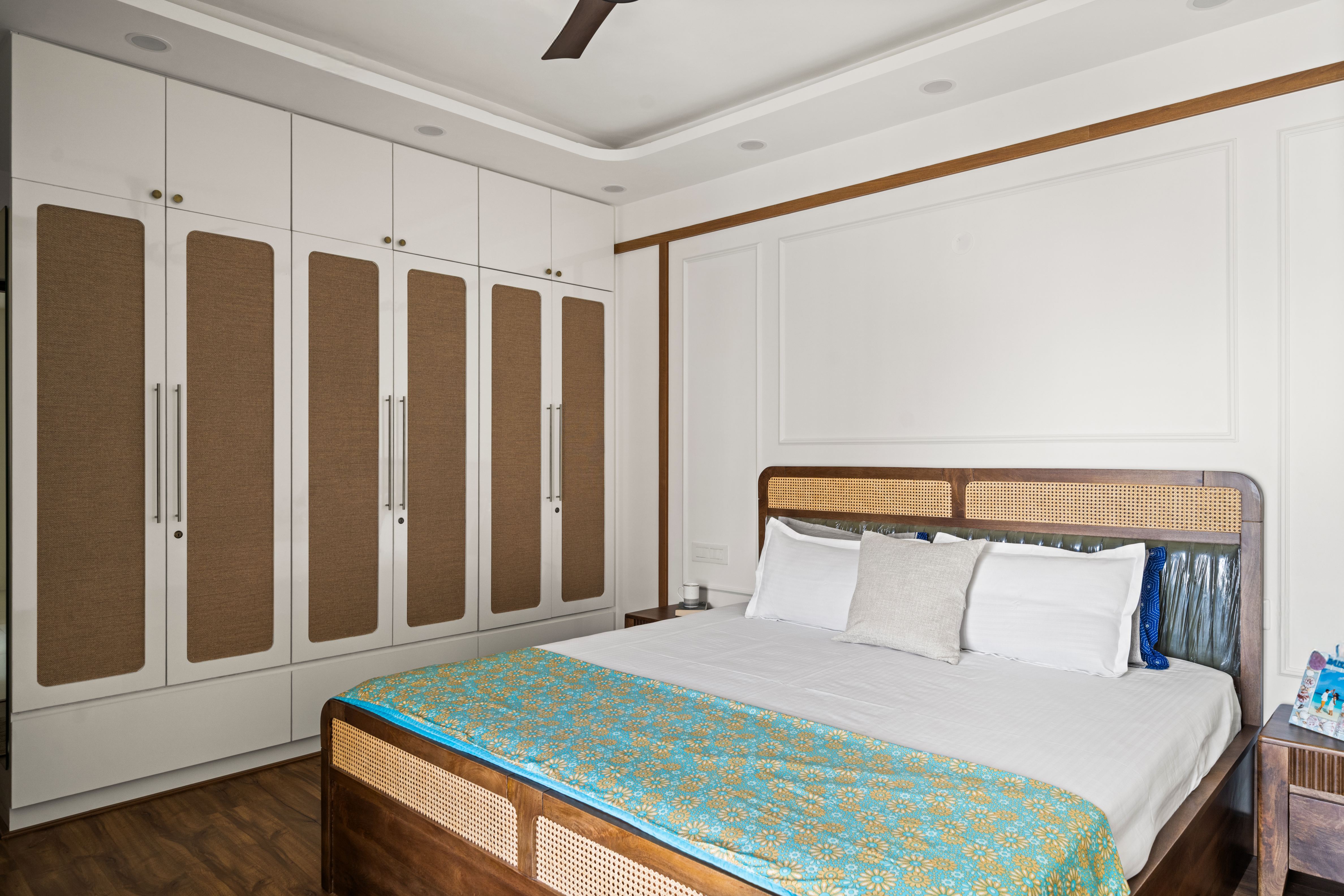 Scandinavian bedroom with white and natural cane wardrobe, wooden flooring, and cane bed backrest of 2 BHK in Purva Palm Beach Hennur Bengaluru | Material Depot