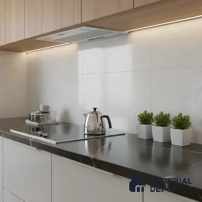 Modern kitchen with black marble-look countertop, light wood laminate cabinets, and large white wall tiles