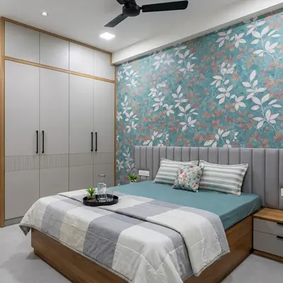 Modern bedroom with floral wallpaper, grey upholstered headboard, and dual tone wardrobe