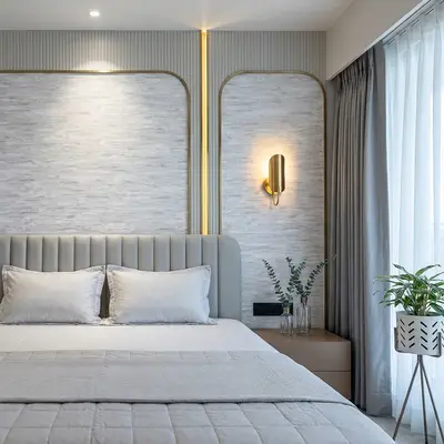 Modern bedroom with grey textured wallpaper, suede upholstered bed, and gold accent profiles